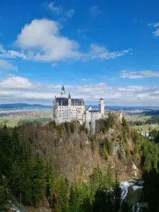 Neuschwanstein Castle in the Bavarian countryside under a blue sky with clouds
